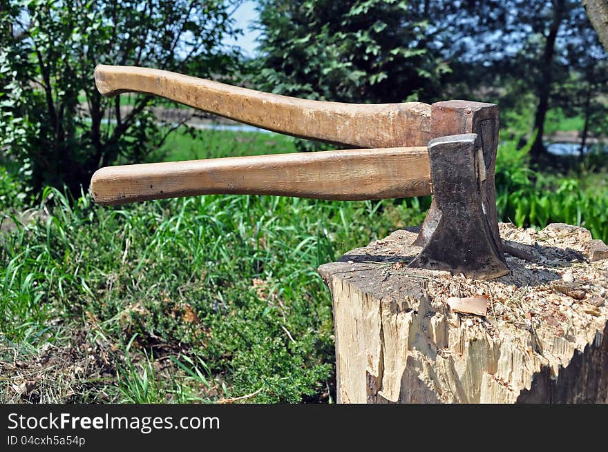 Two axes stuck in a wooden chopping block. Two axes stuck in a wooden chopping block