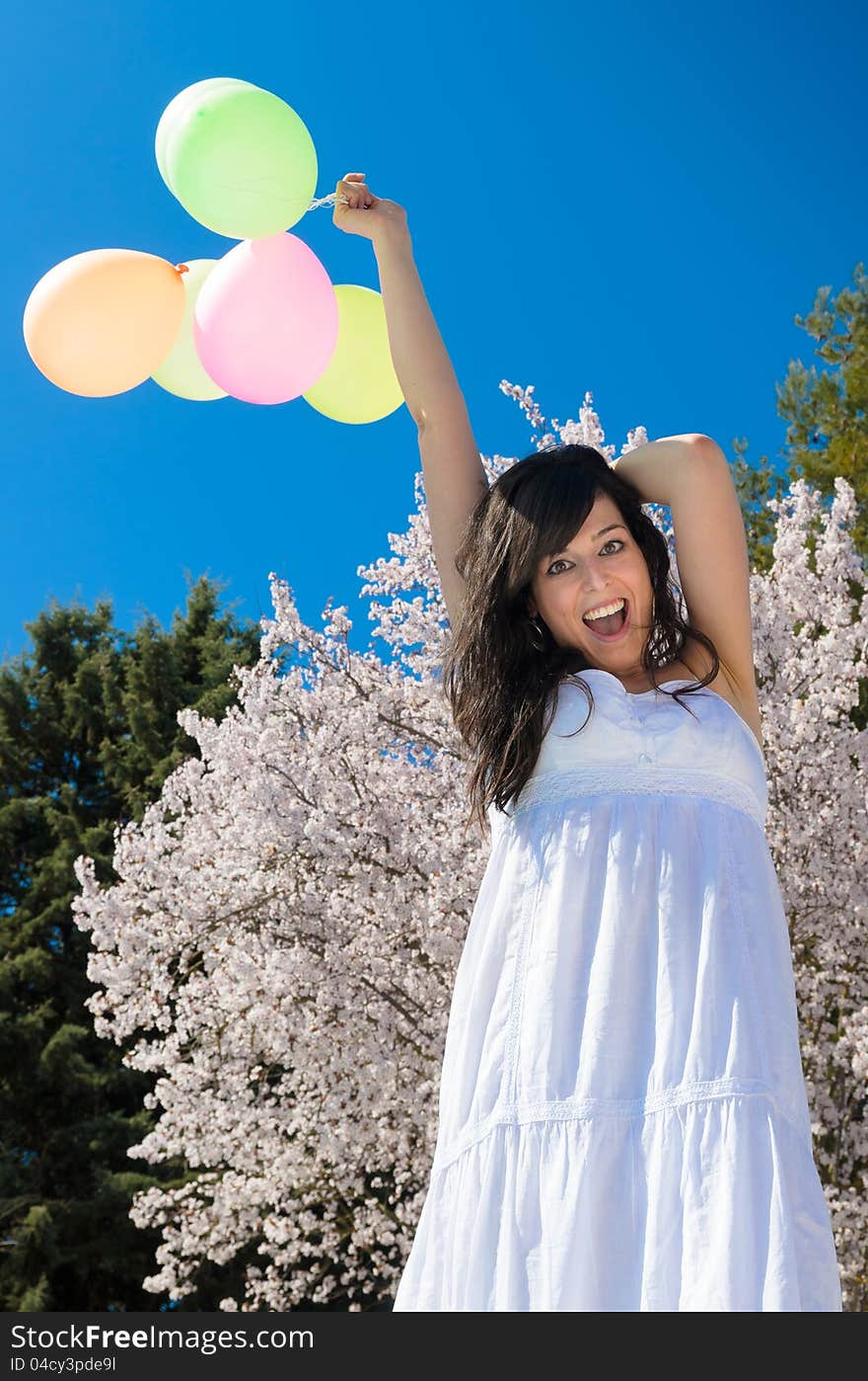 Young beautiful woman playing with colorful balloons, smiling and celebrating love and life in a spring scene. Young beautiful woman playing with colorful balloons, smiling and celebrating love and life in a spring scene.