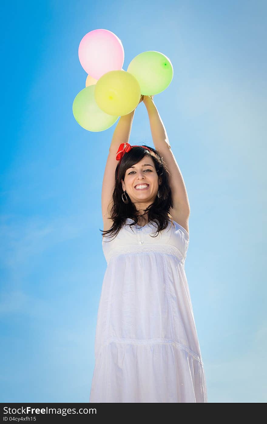 Beautiful brunette woman shows her happiness playing and having fun with colorful balloons. Beautiful brunette woman shows her happiness playing and having fun with colorful balloons.