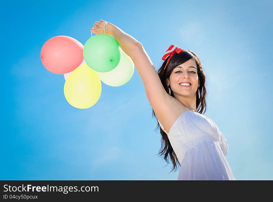 Beautiful brunette woman shows her happiness playing and having fun with colorful balloons. Beautiful brunette woman shows her happiness playing and having fun with colorful balloons.