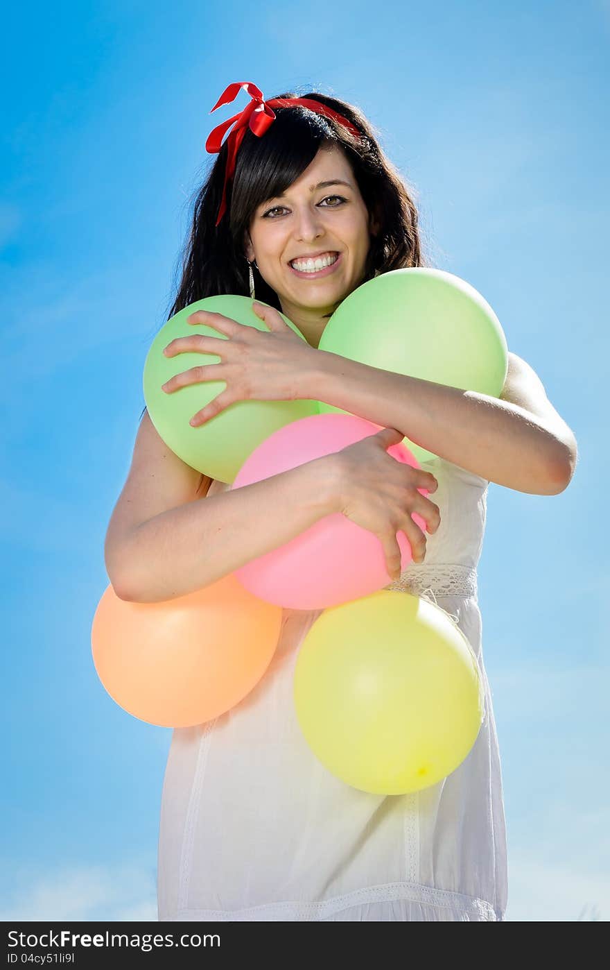 Beautiful brunette woman shows her happiness and love playing and having fun with colorful balloons. She is hugging the balloons. Beautiful brunette woman shows her happiness and love playing and having fun with colorful balloons. She is hugging the balloons.