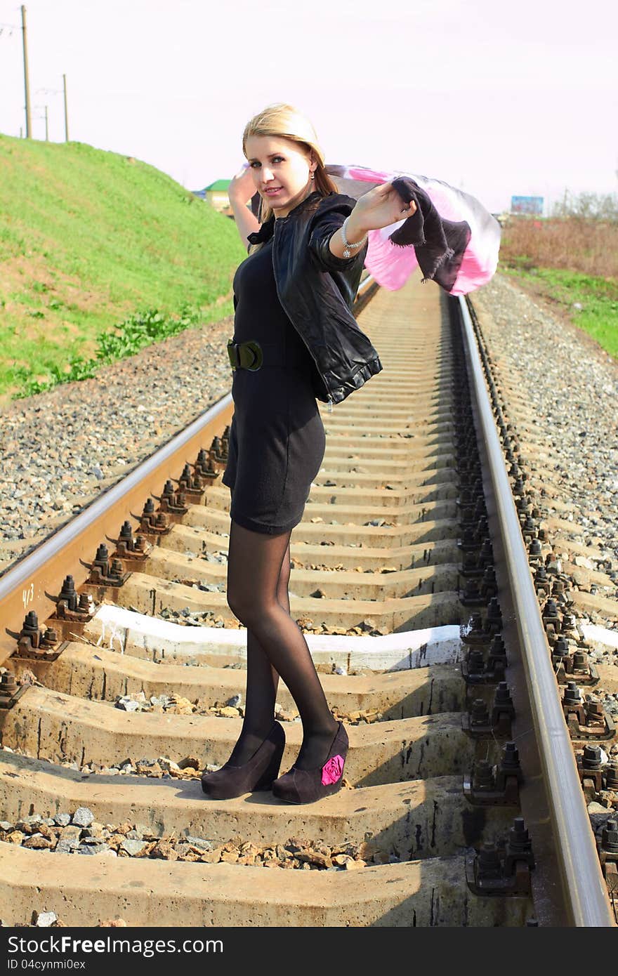 Attractive young girl standing on railroad tracks