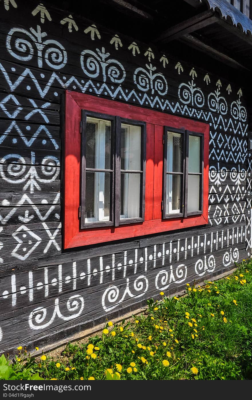 Colorful red windows on traditional Slovak wooden cottage