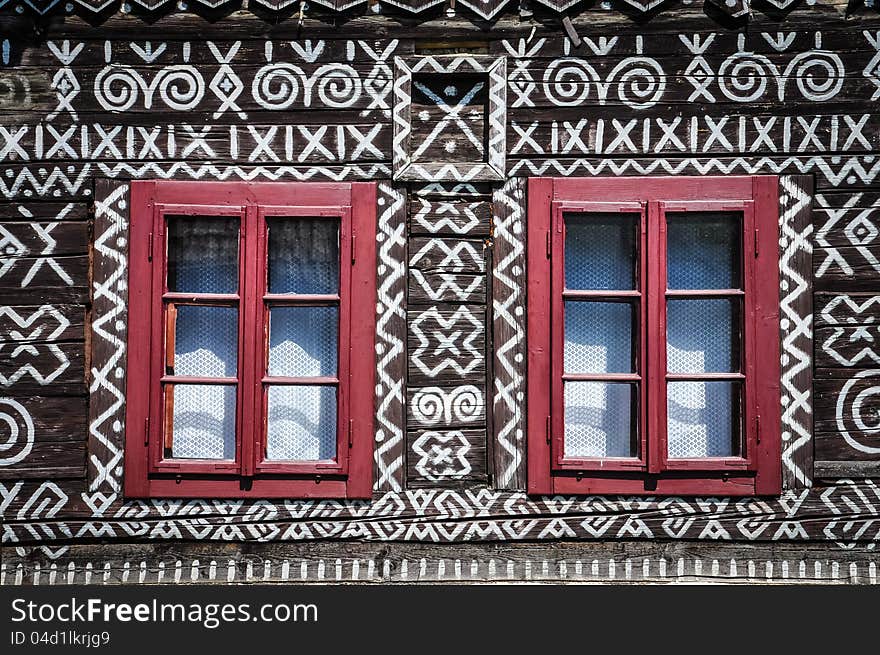 Red windows on wooden wall of traditional cottage, Cicmany, Slovakia