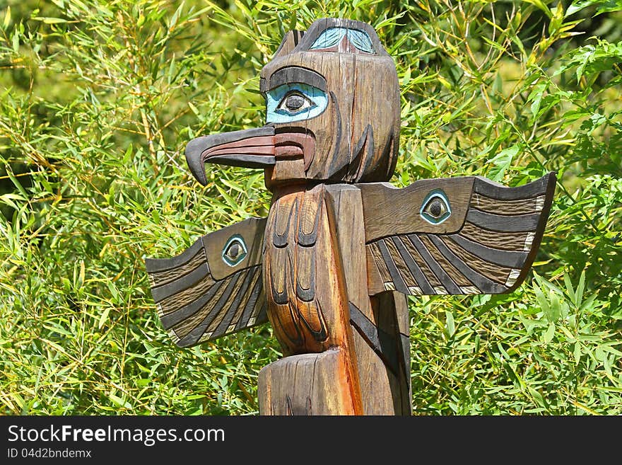 Hand Carved and Painted Wood Totem Pole With Bright Green Background