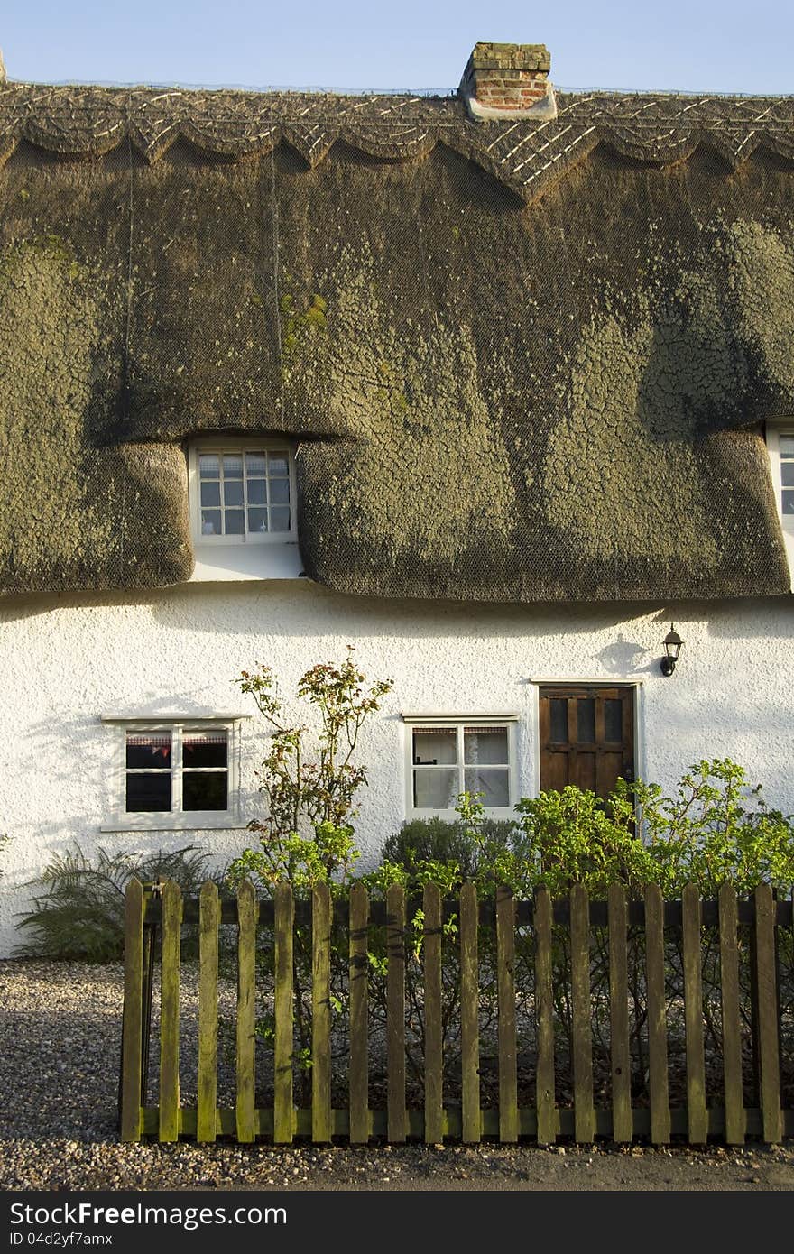 Traditional home nestled behind garden fence in in small village in England. Traditional home nestled behind garden fence in in small village in England