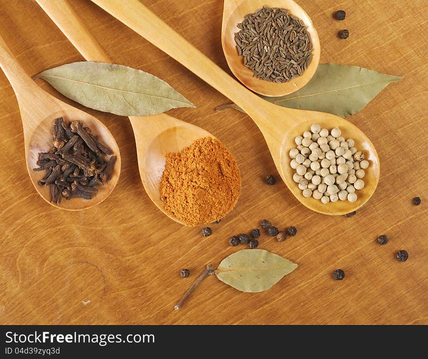 Spices in the spoons on wooden background