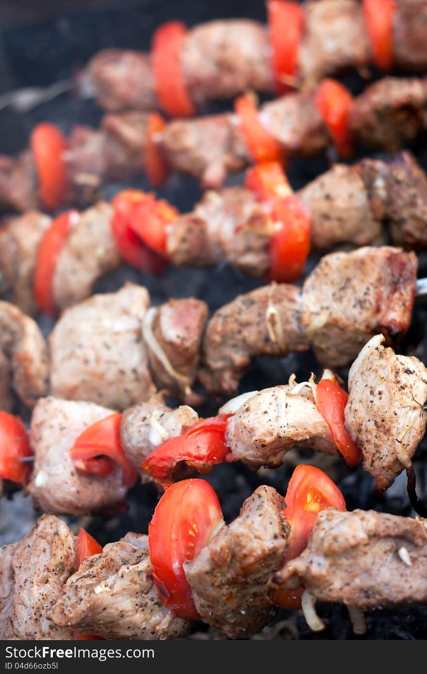 Pieces of meat and tomatoes on the grill close up. Pieces of meat and tomatoes on the grill close up.