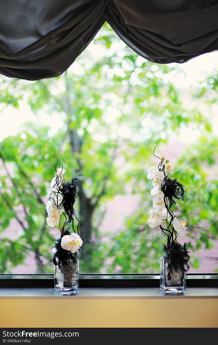 White flowers are in a vase on a windowsill. White flowers are in a vase on a windowsill