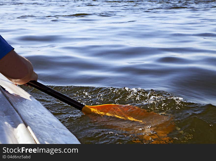 Kayak paddle on side of a boat at still river water. Kayak paddle on side of a boat at still river water