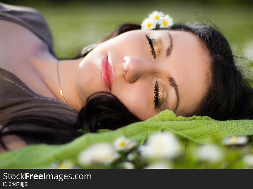 The image of a beautiful girl lying on the grass with flowers