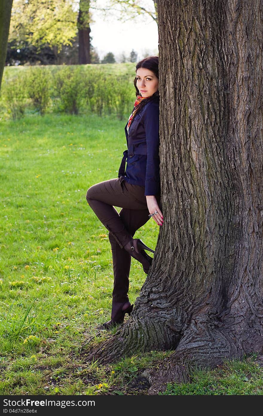 Beautiful young girl near tree in the park