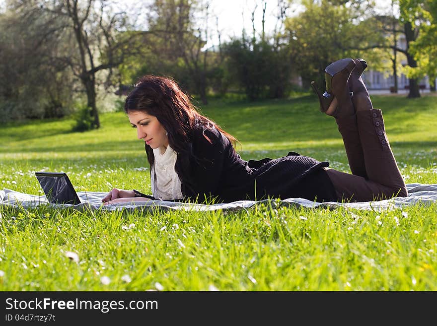 Young woman working with net-book outdoors in park on grass. Young woman working with net-book outdoors in park on grass