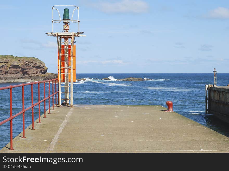 Harbour light on pier, railings, sea and cliffs at Eyemouth, Berwickshire. Harbour light on pier, railings, sea and cliffs at Eyemouth, Berwickshire