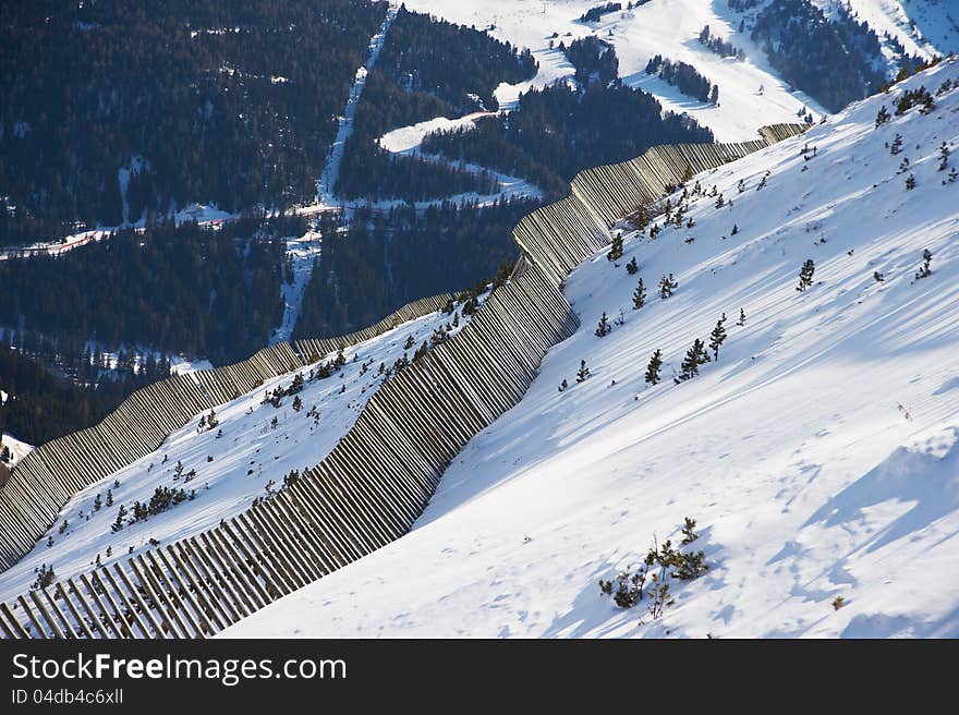 View of the valley from the mountainside with an avalanche fence