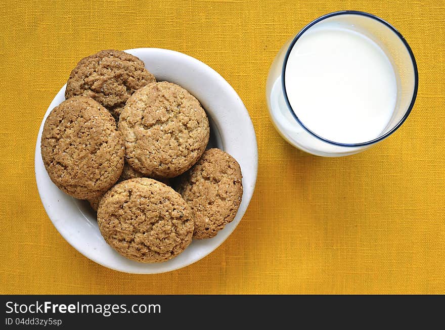 White plate with oat cookies and glass with milk