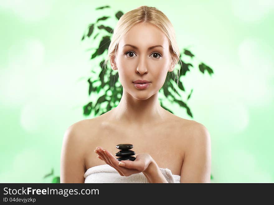 Beautiful blonde with zen stones in hand over green background