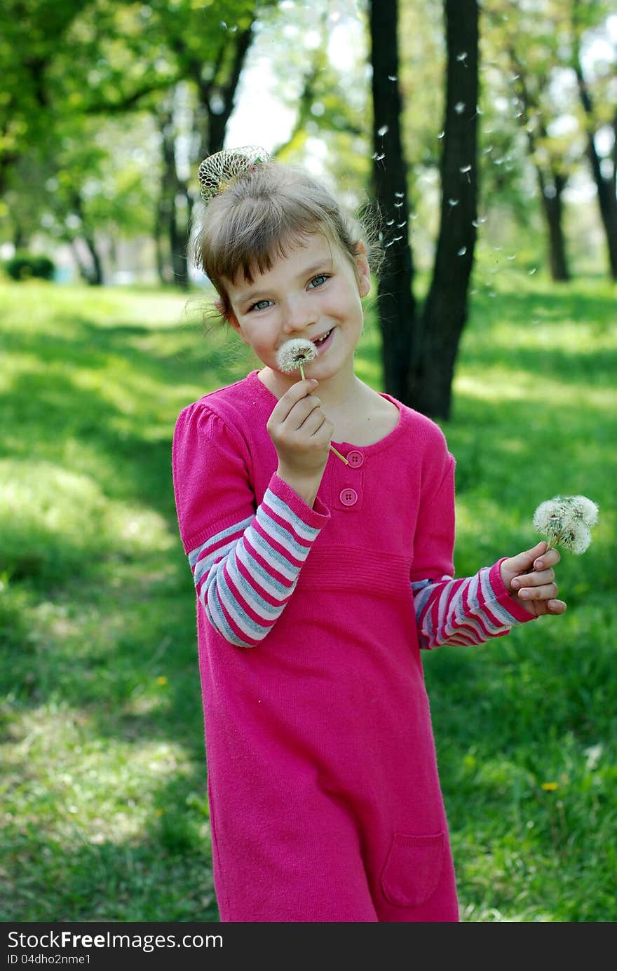 The first spring flowers. The little girl in a pink dress looks into the camera. The first spring flowers. The little girl in a pink dress looks into the camera