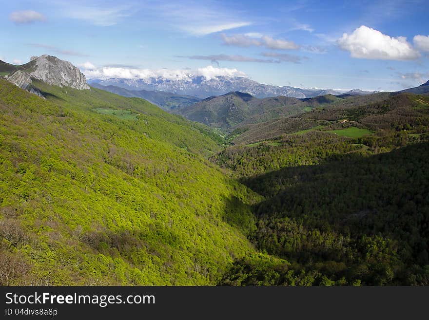 Mountains covered of lush forests seen from Piedras Luengas viewpoint on a shiny spring day with high mountains covered with snow on the background. Mountains covered of lush forests seen from Piedras Luengas viewpoint on a shiny spring day with high mountains covered with snow on the background