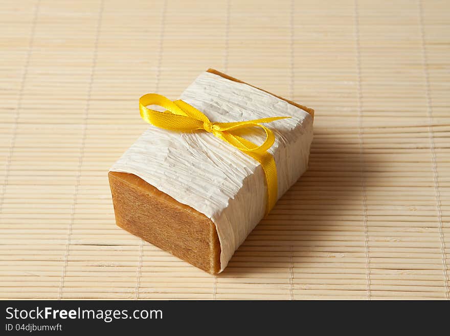 Natural soap tied with a ribbon on a bamboo mat