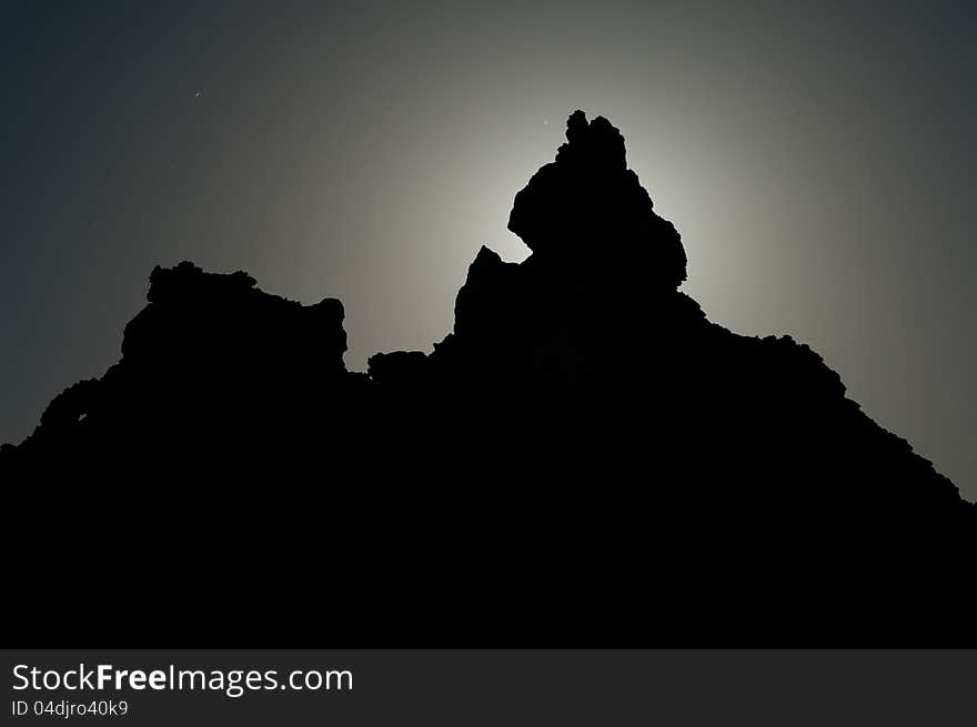 Dark Jagged Peak is Silhouetted in the moon light. Faint stars can be seen at night. Dark Jagged Peak is Silhouetted in the moon light. Faint stars can be seen at night.