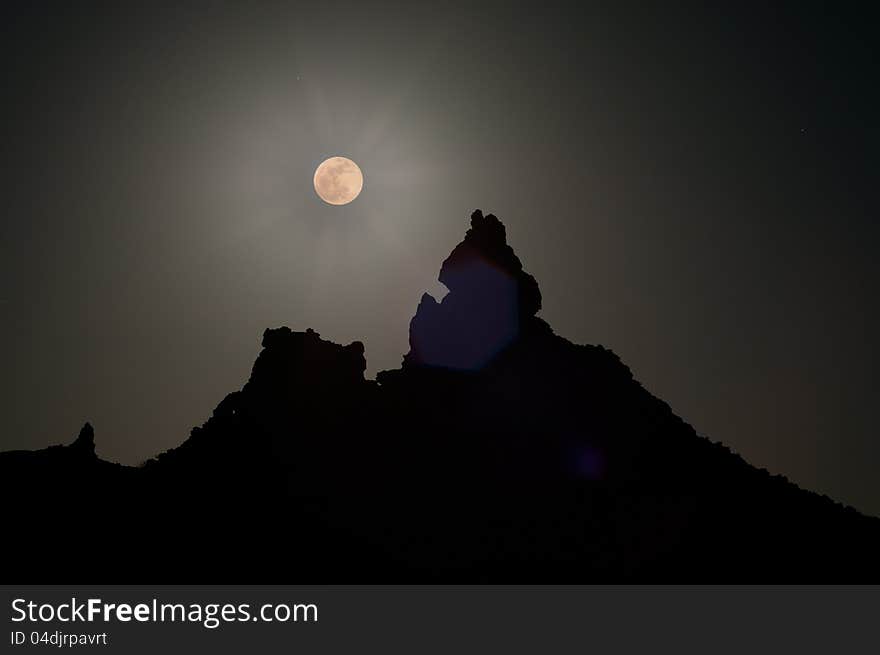 Super Moon over silhouetted peak