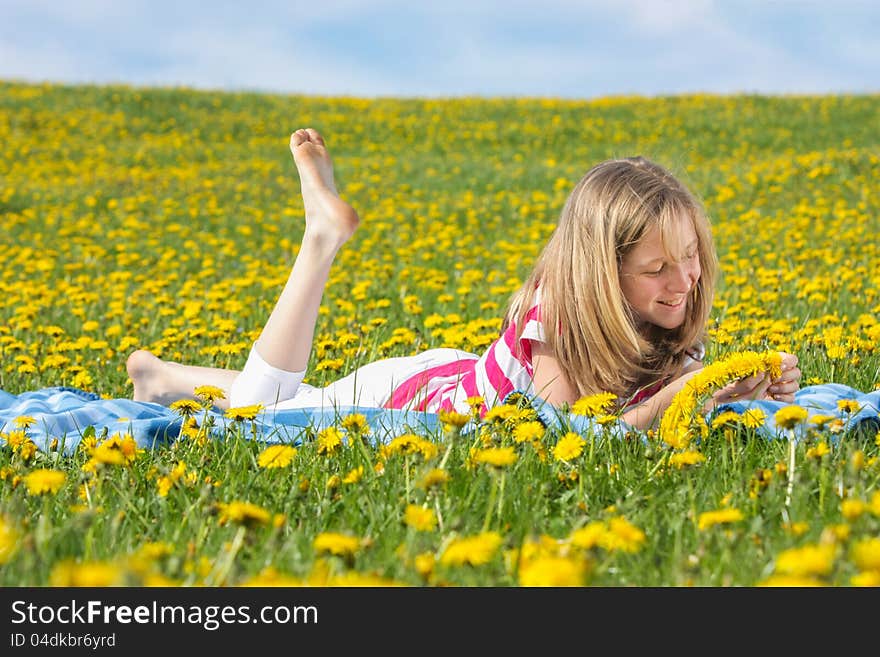 Teenage girl lying on a dandelion field