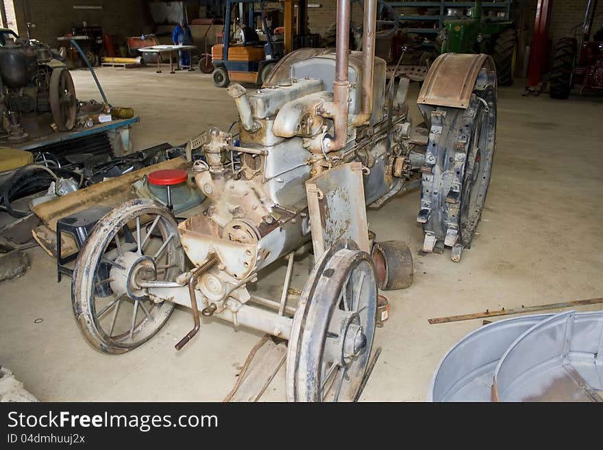 A very old vintage tractor in a untidy workshop. A very old vintage tractor in a untidy workshop