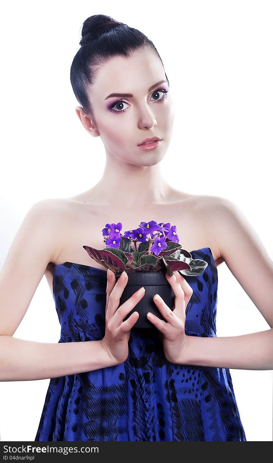 Beautiful young woman with flowers in blue dress posing in studio. Beautiful young woman with flowers in blue dress posing in studio