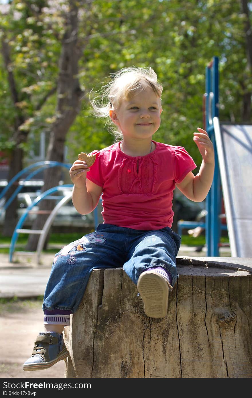 Little girl sitting on a stump and laughing. Little girl sitting on a stump and laughing