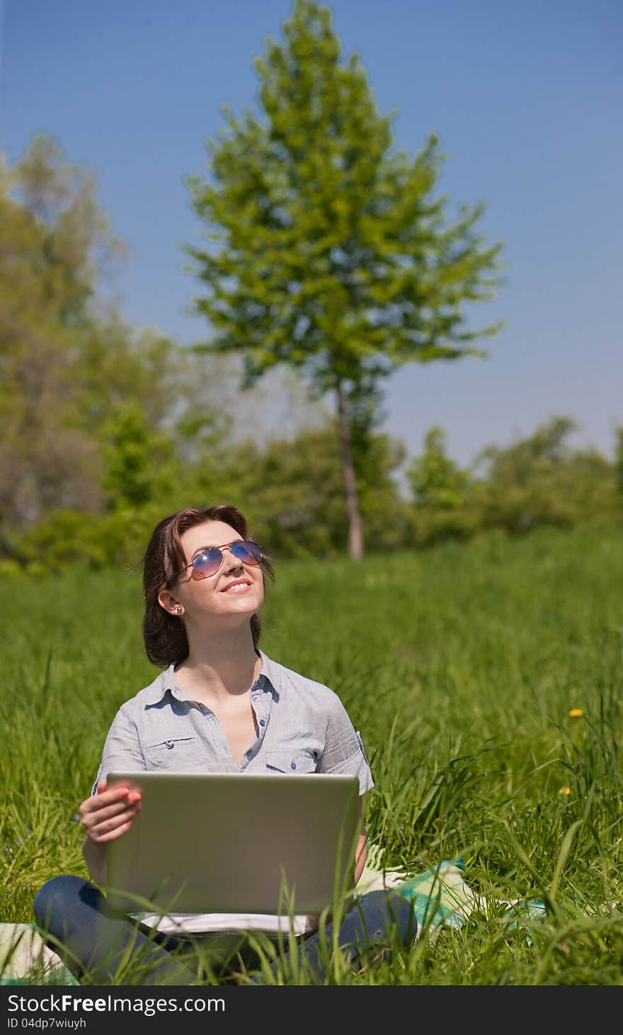 Young woman with laptop on a green grass in the park