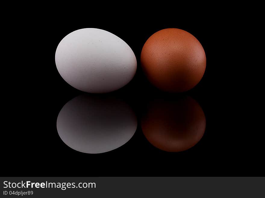 Two chicken eggs on black background.