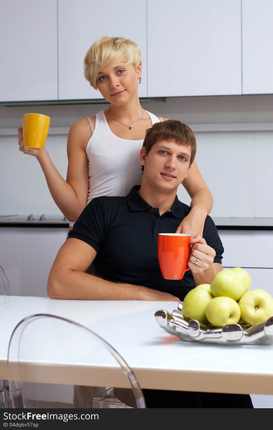 Portrait of a happy couple posing in the kitchen with cups and lemons on the table