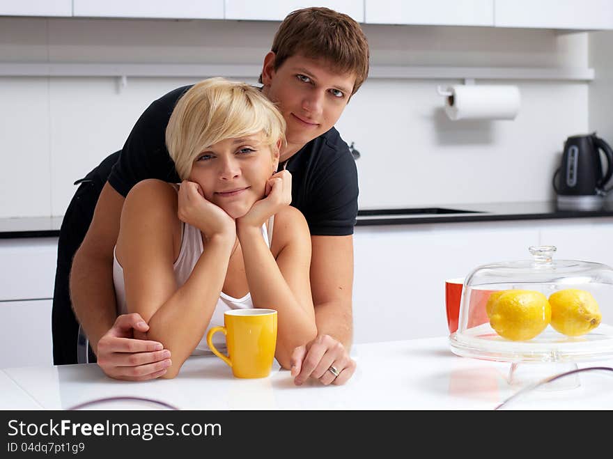 Portrait of a happy couple posing in the kitchen with cups and lemons on the table