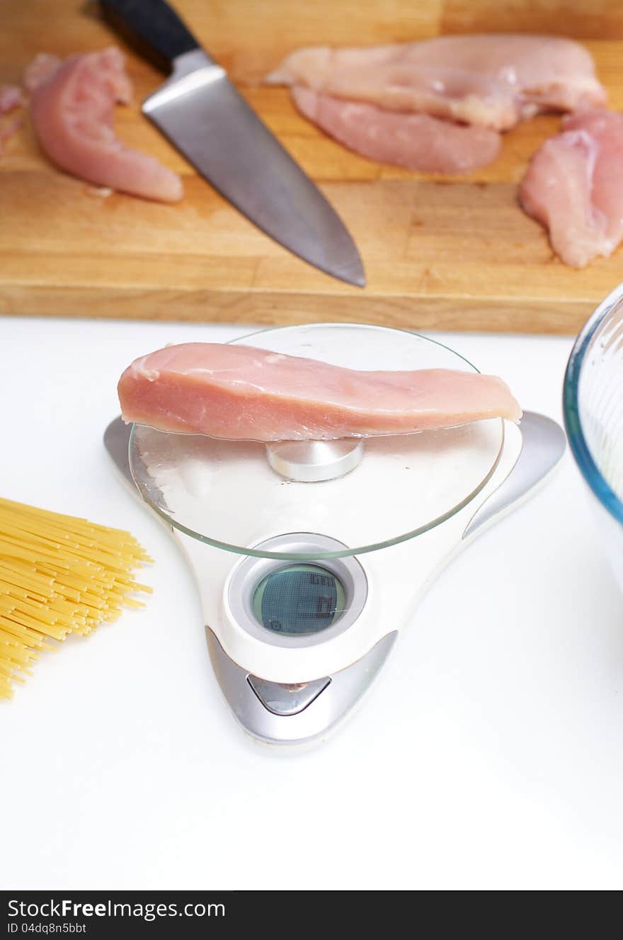 Chicken slice stacked on a scale standing on table