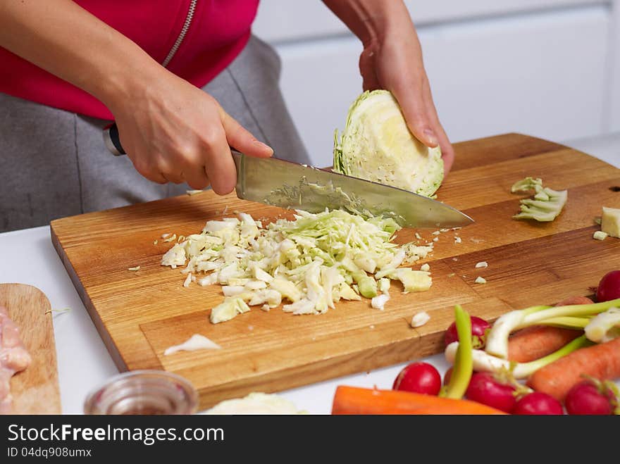 Female hands slicing cabbage