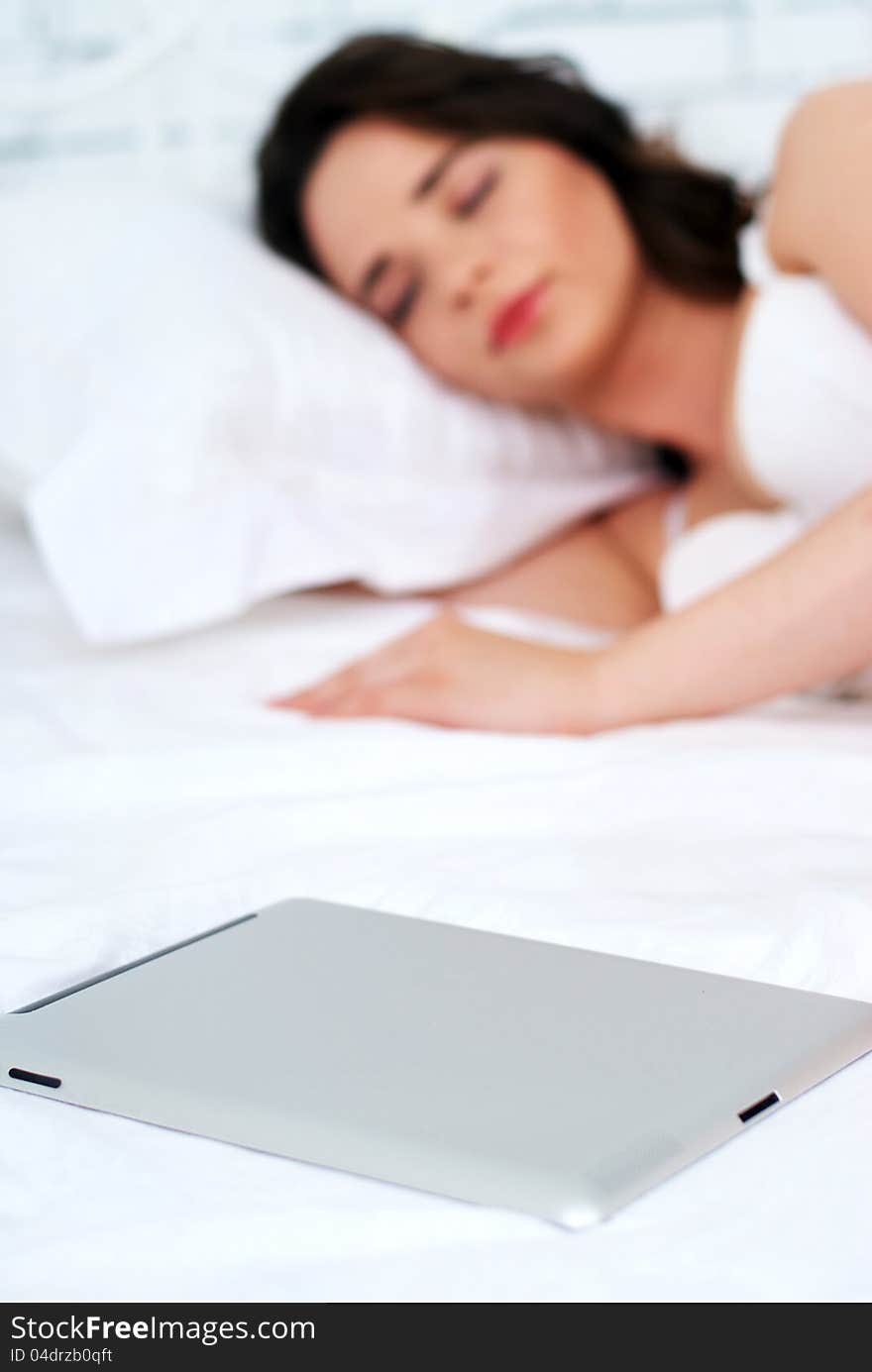 Beautiful emotional young woman using tablet computer in her bedroom high key. Beautiful emotional young woman using tablet computer in her bedroom high key