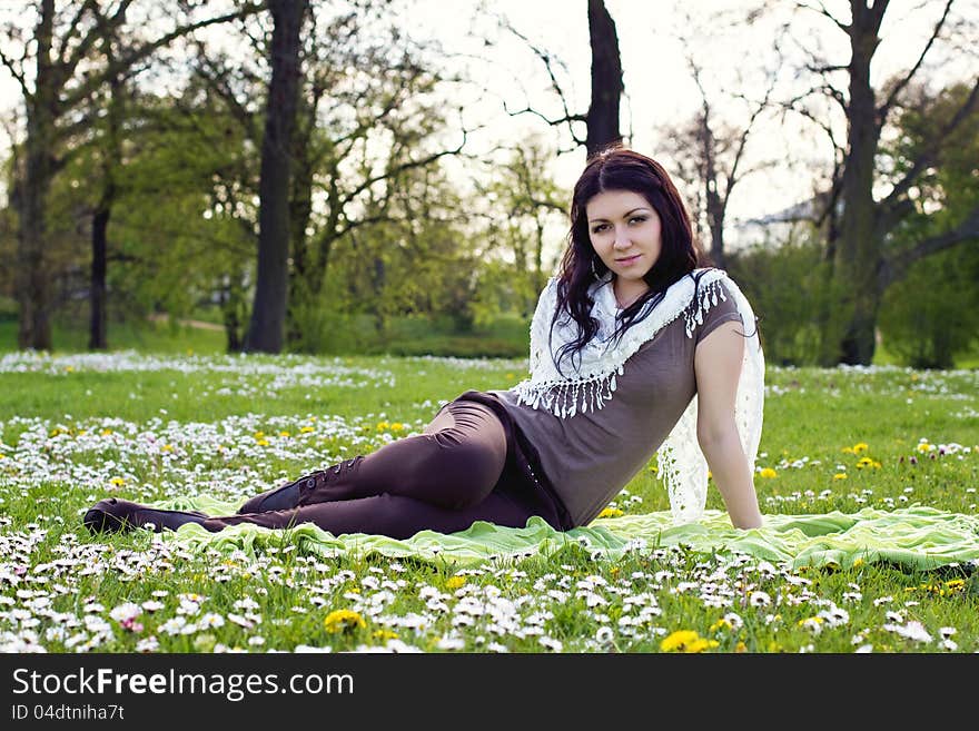 Beautiful girl sitting on the plaid in the park