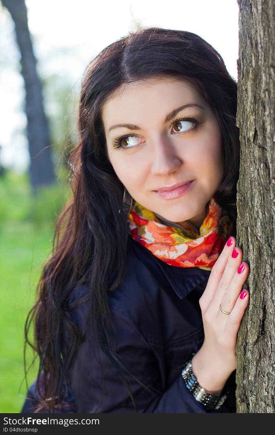 Beautiful young girl near tree in the park