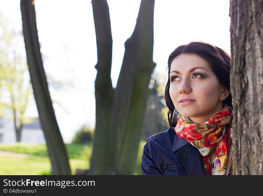 Beautiful young girl near tree in the park