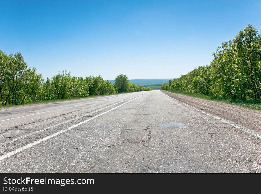 Asphalt highway running down the hill. No clouds