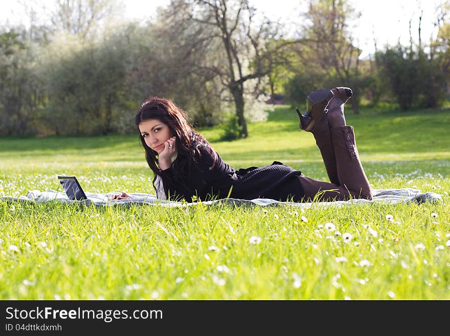 Young woman working with net-book outdoors in park on grass. Young woman working with net-book outdoors in park on grass