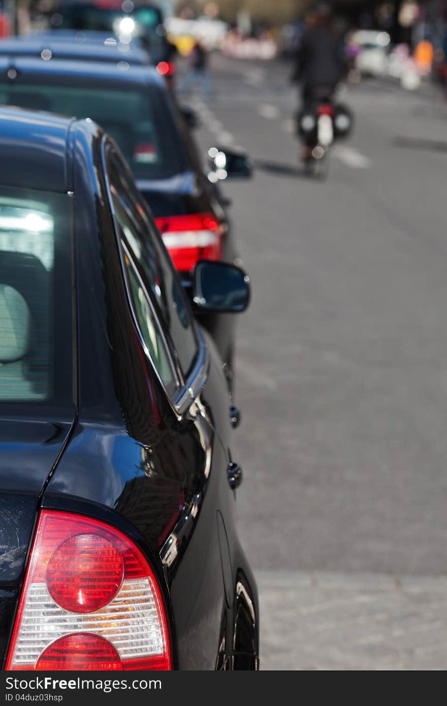 Parked cars along the city road with a cyclist out of focus in the background. Parked cars along the city road with a cyclist out of focus in the background