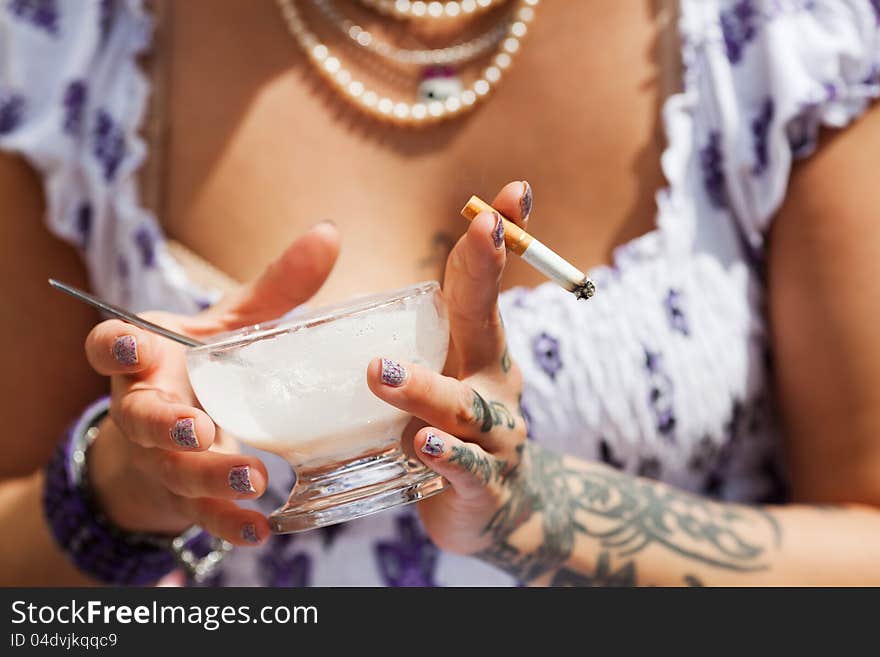 Young woman with tattoos eats an ice and smokes