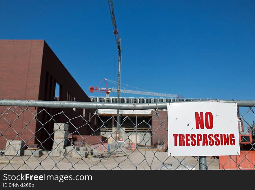 Image of a cluttered construction site that is fenced with a warning sign No trespassing