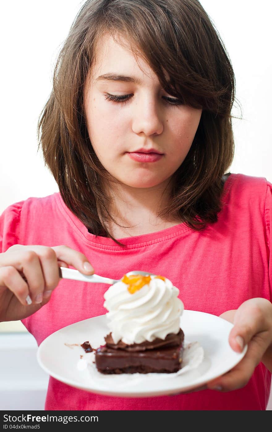 Fun teen girl eating the cake on the white background .Portrait of young woman eating cake isolated on white background