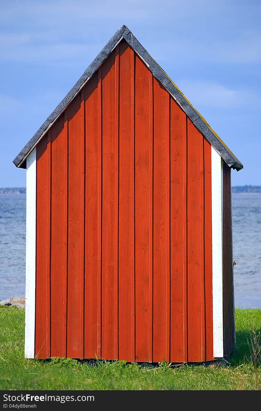 Red boathouse with blue sky and water in background