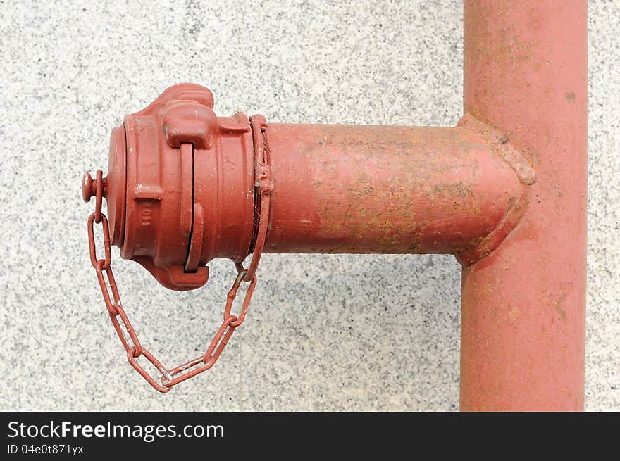 A red fire hydrant by the wall