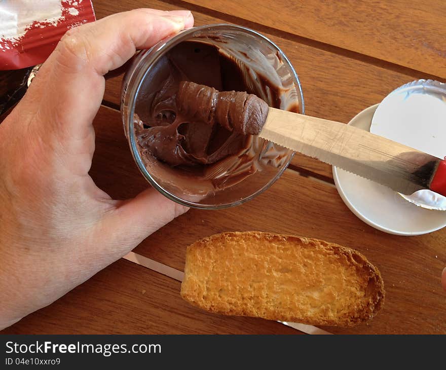 Woman smears the chocolate on the bread