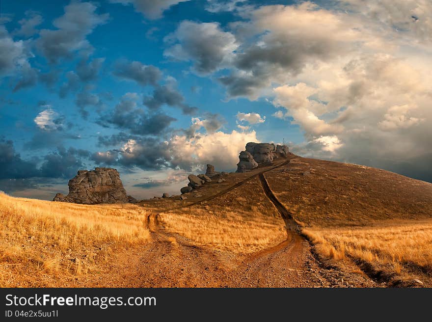 Landscape witn road to the mountains peak and majestic clouds on background